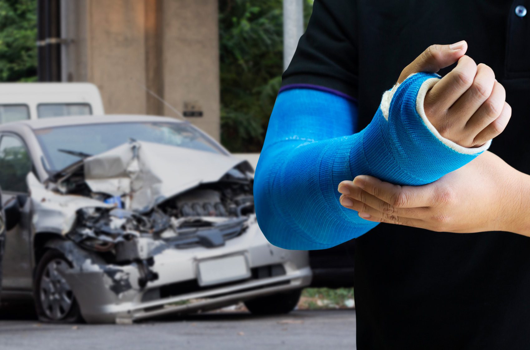 Close-up-of-man-with-a-blue-arm-cast-with-car-accident-in-the-background