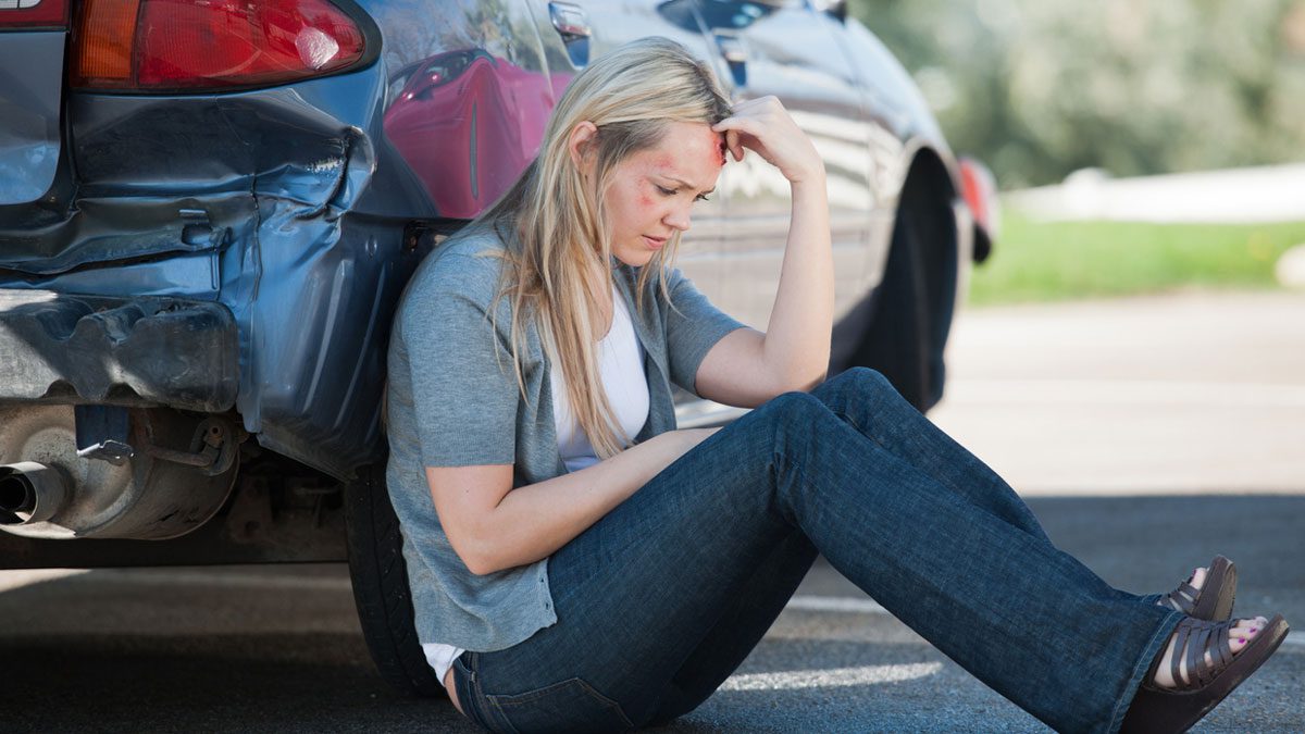 Female accident victim waits outside of her car