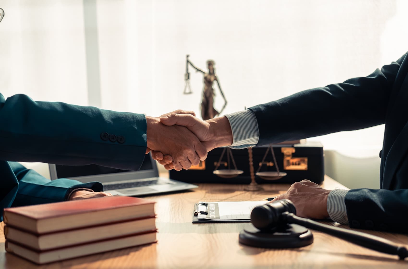close-up of lawyer and client shaking hands over table