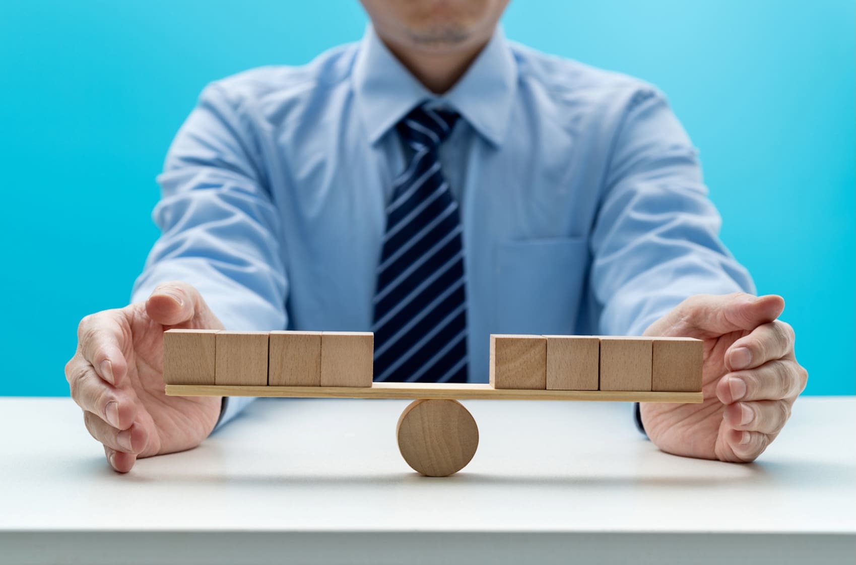 man balancing blank cubes on wooden seesaw