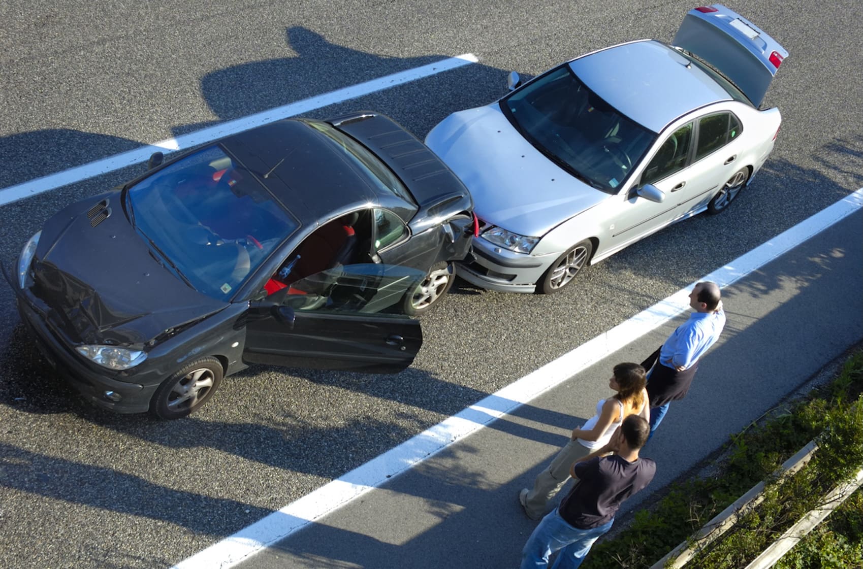 three people stand by the roadside after accident on the freeway